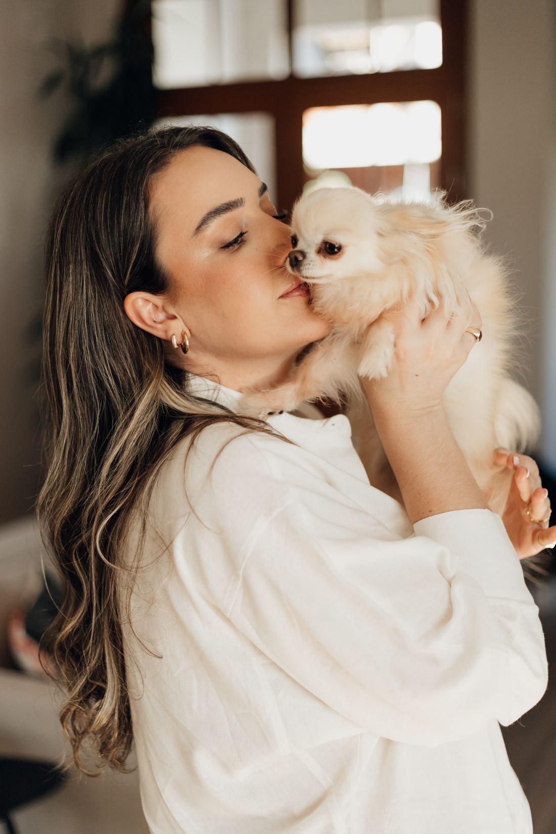 Daniela abraçando um cão pequeno de pelo claro