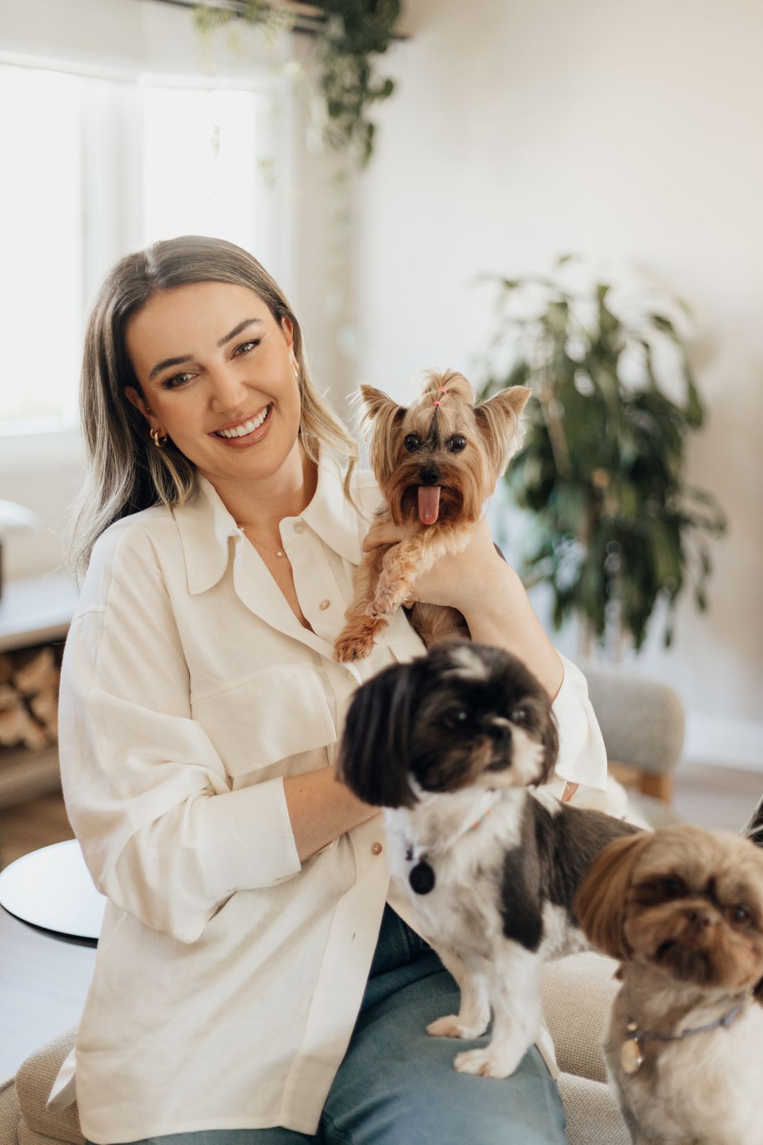 Daniela sorrindo com dois cães no colo